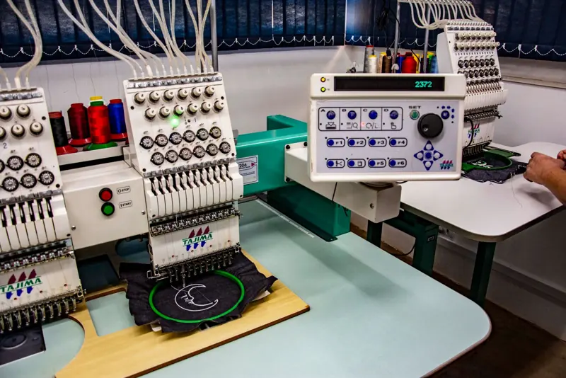 Multi-head embroidery machine stitching a logo held in a hoop