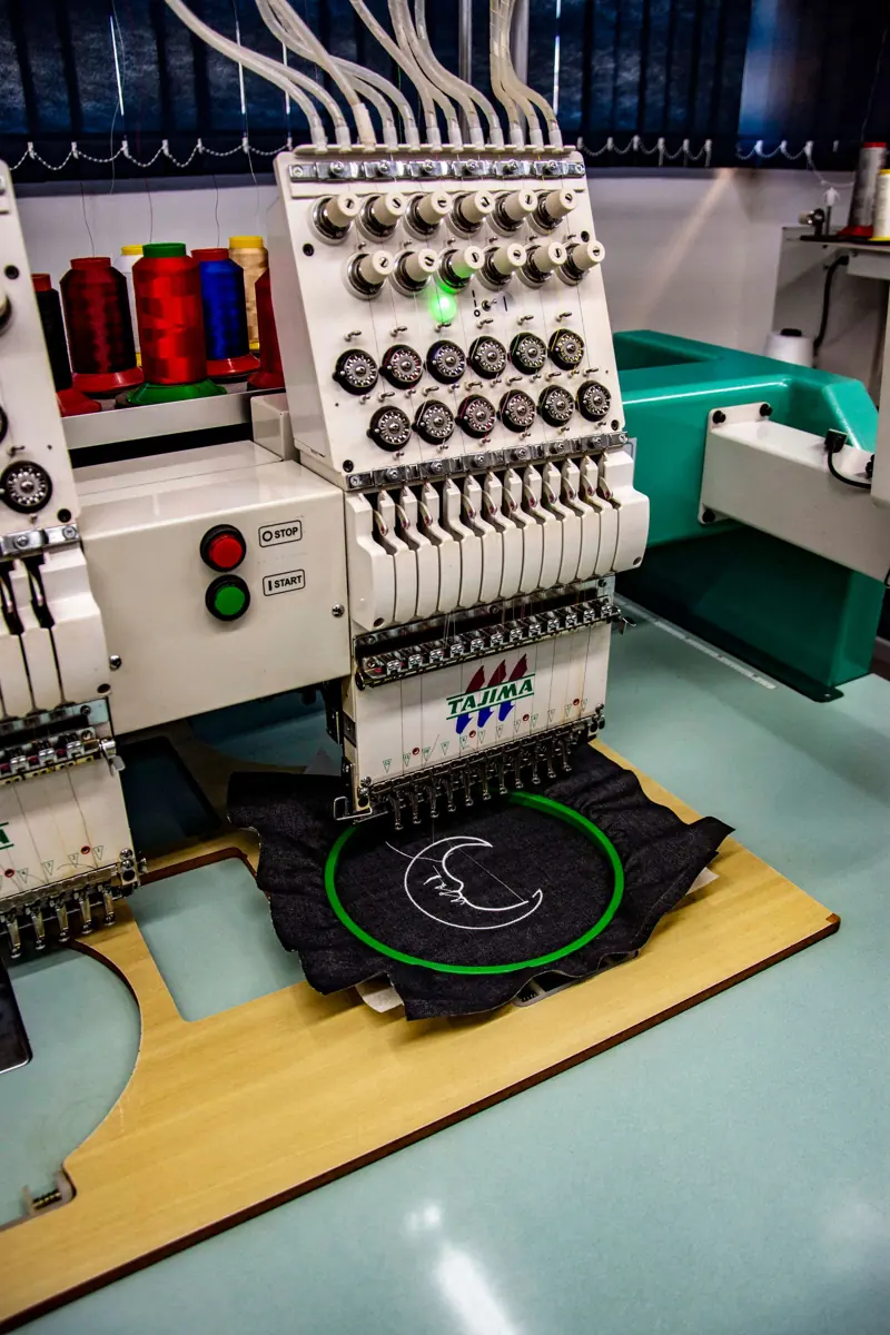 Embroidery machine stitching a logo on a hooped garment